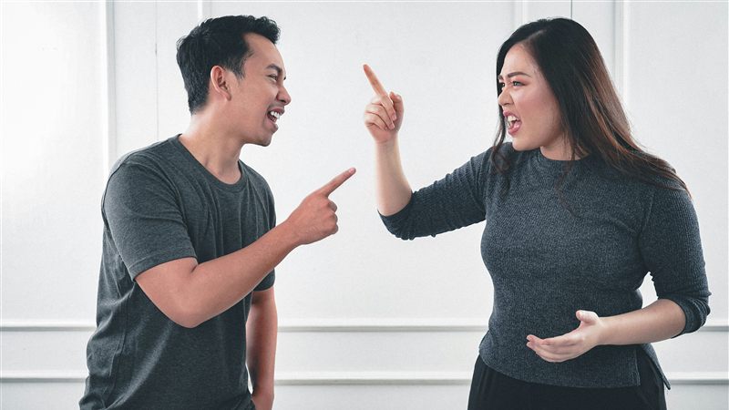 Man and woman in a heated argument, pointing at each other