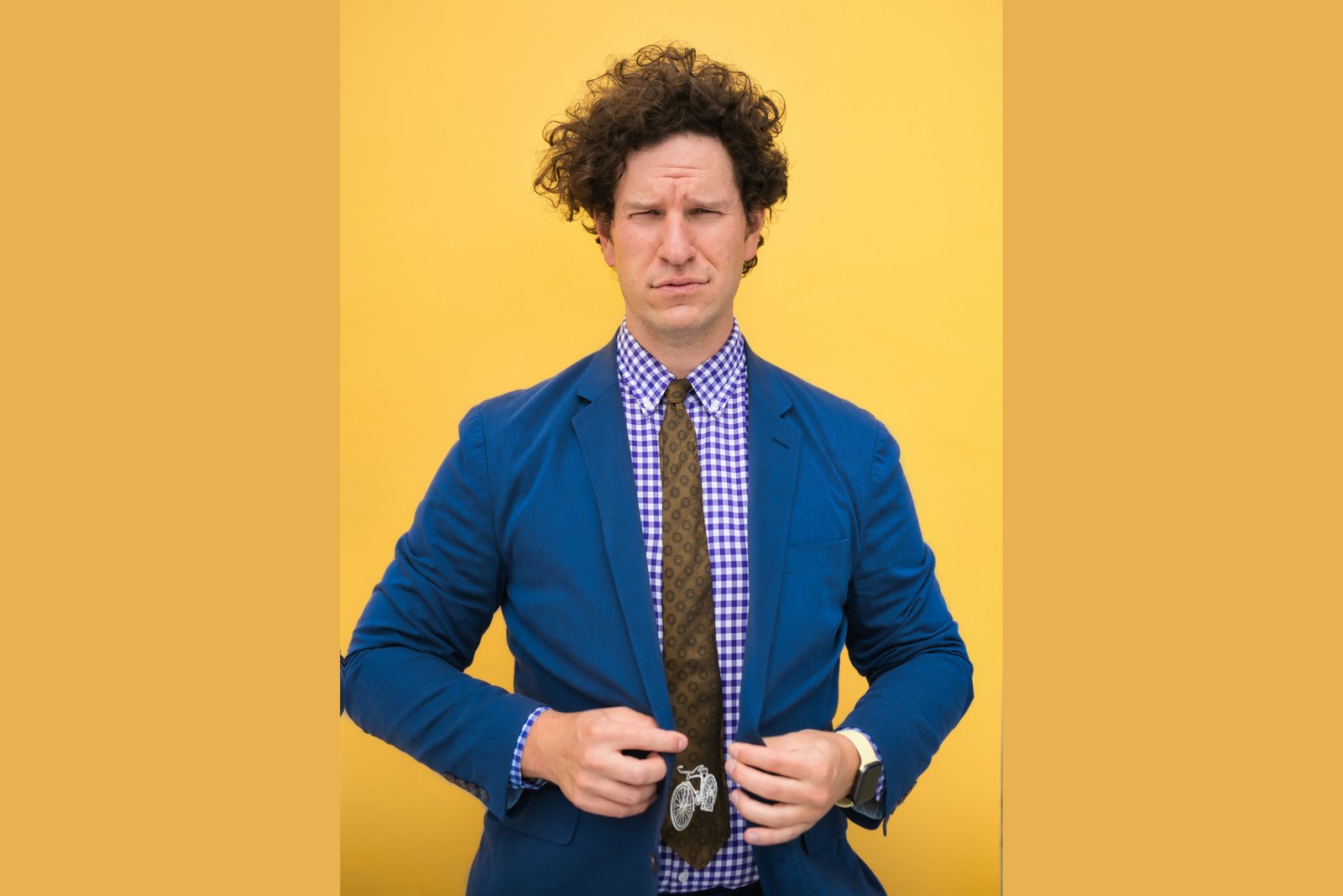 Colorado appellate attorney Daniel H. Kyser raising a skeptical eyebrow in a blue blazer and patterned tie against a yellow background