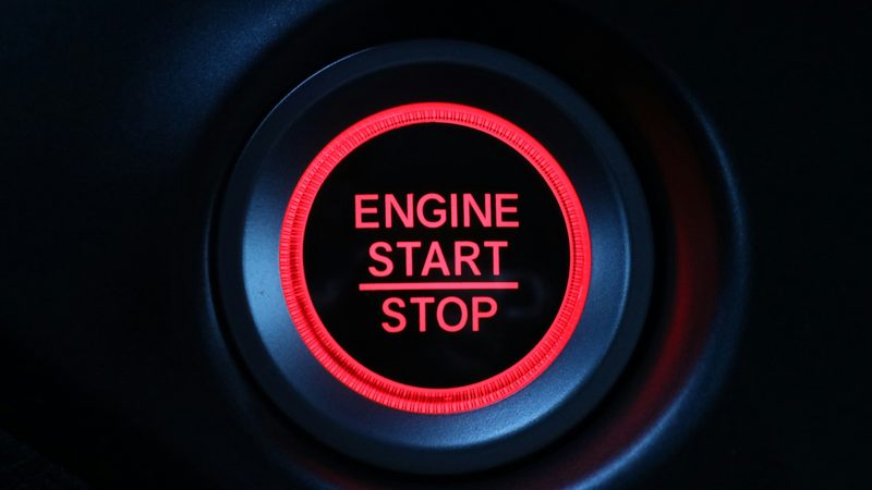 Glowing red ENGINE START/STOP push-button on a car dashboard