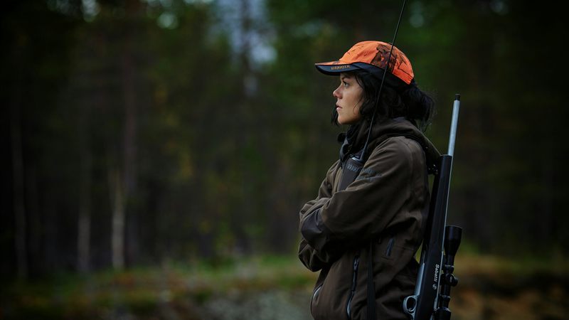 Lawful firearm owner in hunting gear carrying a scoped rifle in the Colorado backcountry