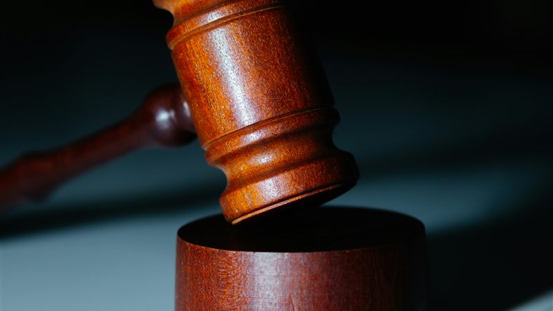 Wooden judge's gavel on a sound block in a darkened courtroom